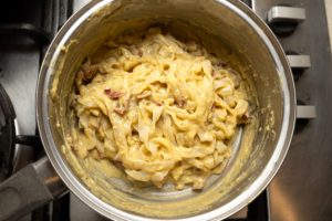Cooked pasta stirred through vegan carbonara sauce