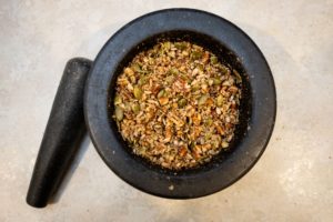 Pecans, sunflower seeds and pumpkin seeds broken up in a mortar and pestle