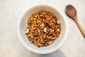 Spices stirred through mixed nuts in a mixing bowl