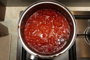 Tinned tomatoes added to pot with onion and garlic