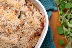 Eggplant parmigiana cooked in baking dish with a spring of fresh oregano to the side