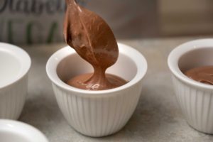 Vegan chocolate mousse being spooned into a ramekin