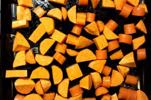 Kumara and carrot on baking tray with oil, salt and pepper